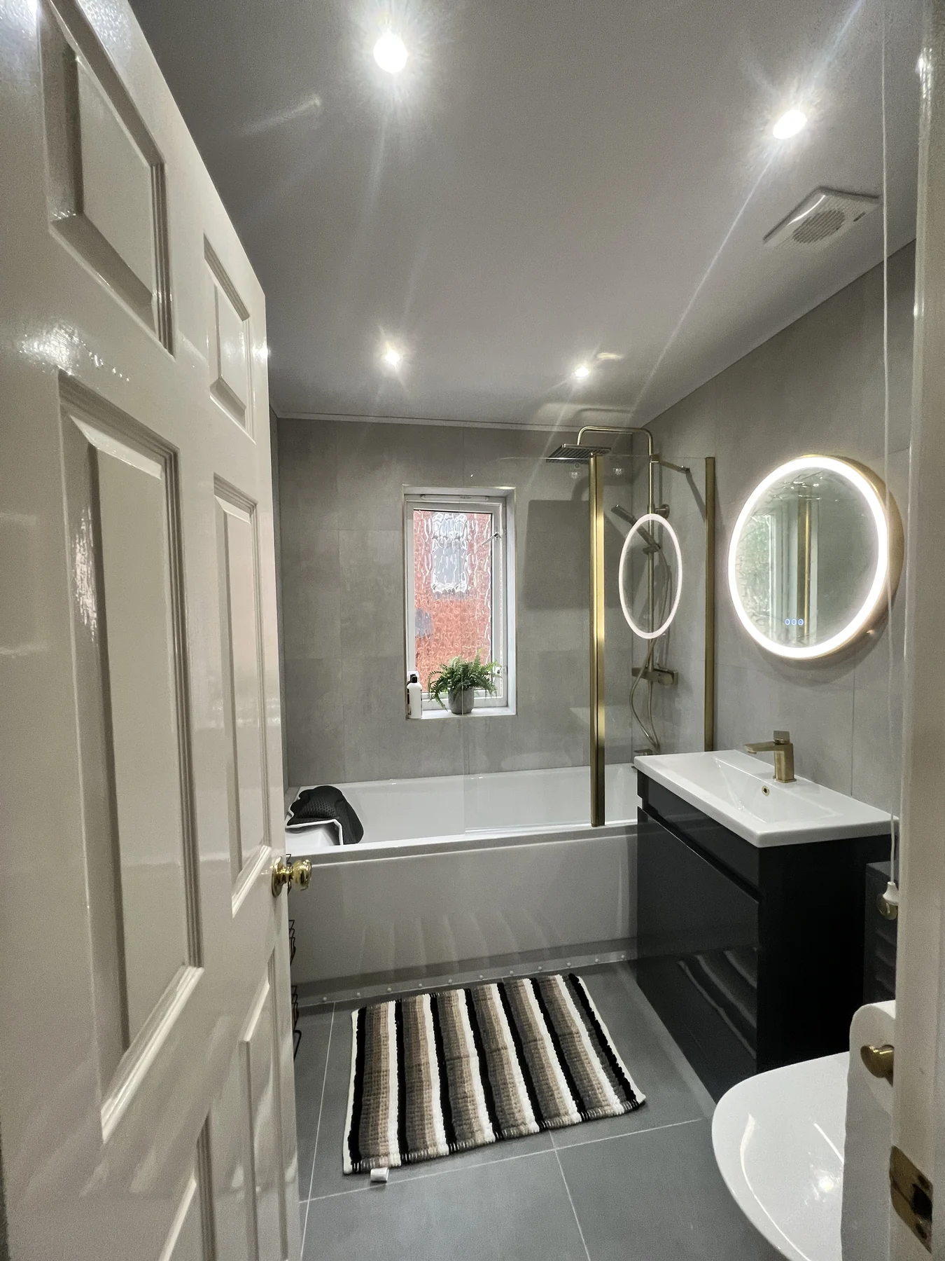 A modern grey and brass family bathroom.