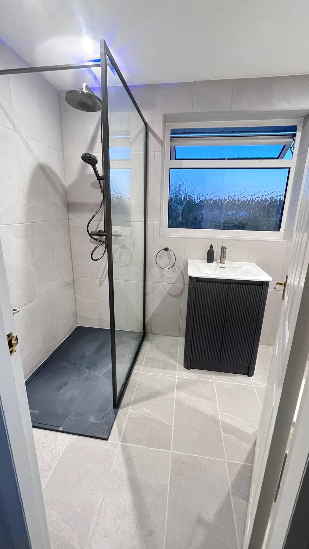 A modern walk-in shower with contrasting black finishes.